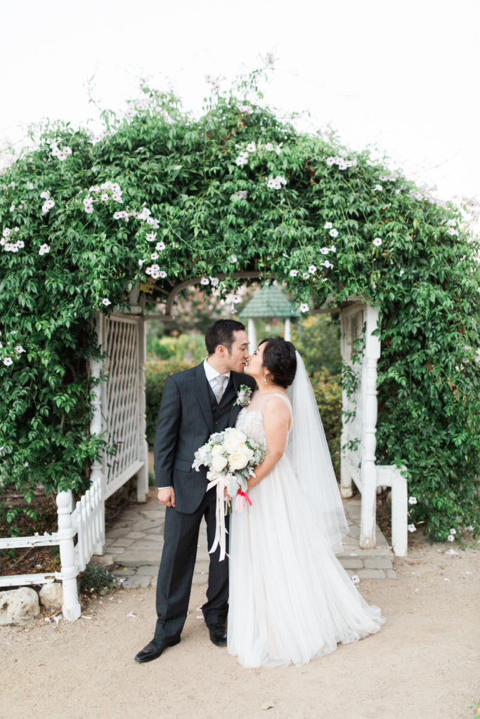 bride and groom in garden under greenery arch