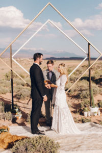 bride and groom under diamond arch in moab utah desert