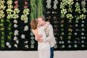 first kiss in front of plant wall