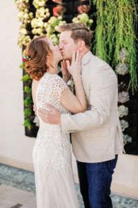 bride and groom kiss in front of succulent wall