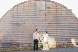 bride and groom in front of warehouse
