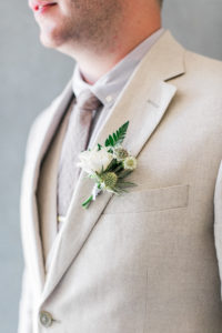 white and green boutonniere on light suit