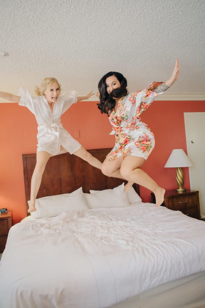 bride and bridesmaid jumping on bed