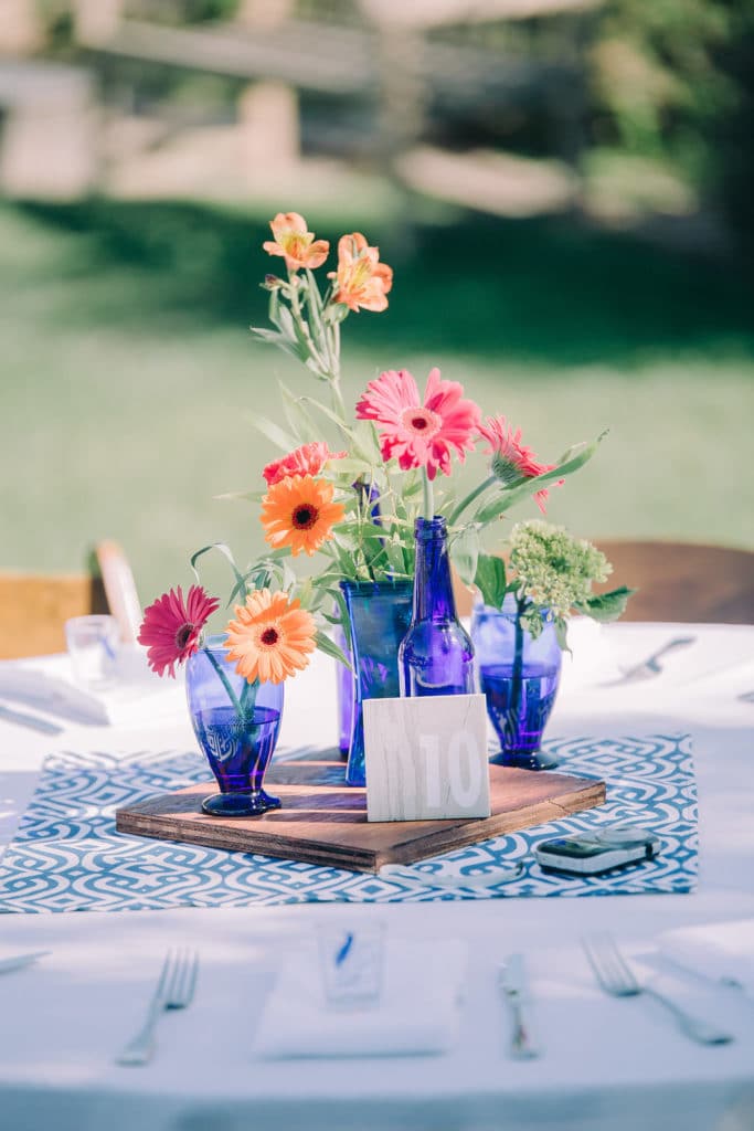 bright orange and pink flowers in clear blue vases