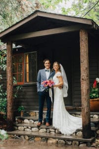 bride and groom in front of log cabin in big sur