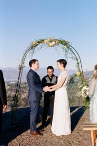 bride and groom under simple arch at treepeople park overlooking los angeles