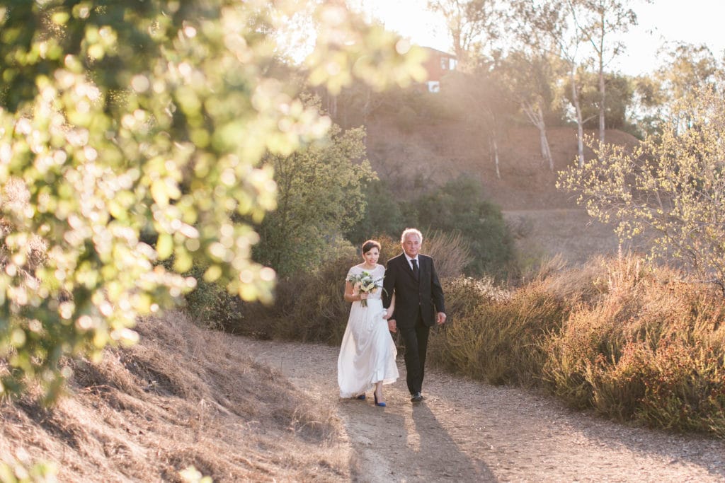 Bride and father walk down the path at TreePeople Park for the ceremony overlooking Los Angeles
