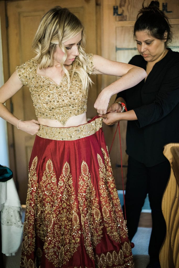 fusion wedding with bride getting in to red and gold lehenga
