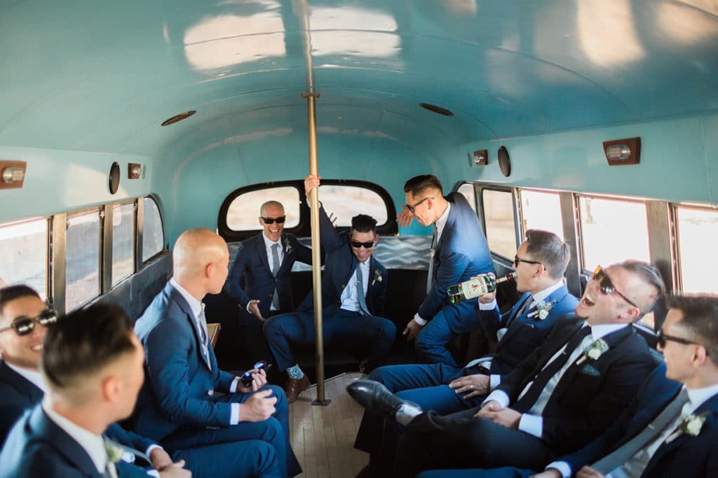 Groom and groomsmen having fun in vintage school bus before wedding ceremony