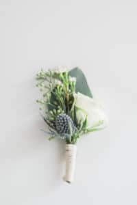 Groom's white floral boutonniere with greenery for barn wedding