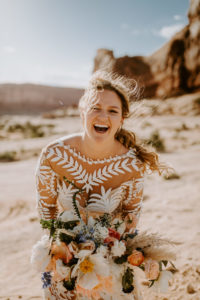 Bride laughing with long messy braid. Desert wedding at Under Canvas Moab