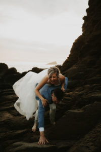 Bride and groom climbing rocks and laughing after elopement in Laguna Beach