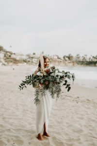 Bridesmaid holding big boho bouquet during elopement in Laguna Beach California