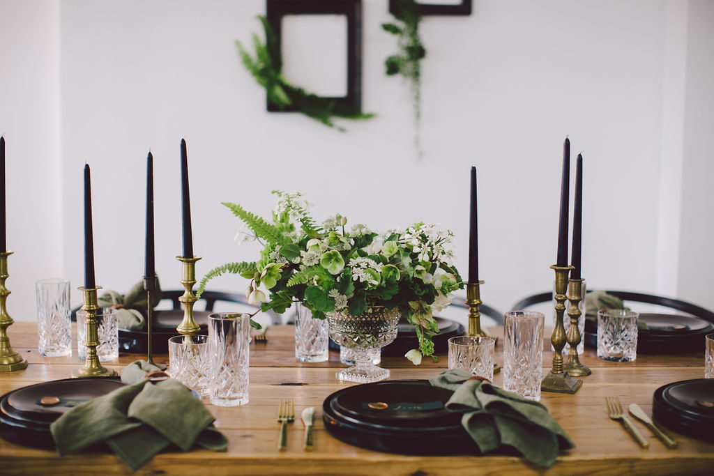St Patrick's Day dinner party with tall black candles and dark green napkins. Black matte chargers, olive green plates and brown top plates for a masculine yet classy St Paddy's Day Dinner Party. 