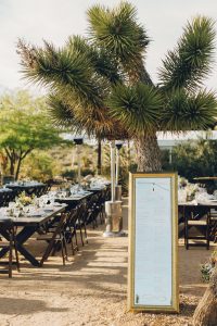 Seating chart written on tall mirror with gold frame at desert wedding
