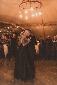 Tattooed bride and groom in all black doing their first dance in a teepee at Under Canvas Zion