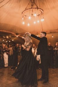 Tattooed bride and groom in all black doing their first dance in a teepee at Under Canvas Zion