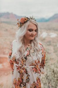Blonde bride with flower crown and white floral robe at glamping wedding in Zion