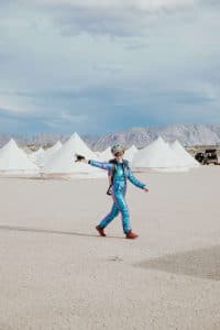 A guest for a Burning Man wedding wears a fun and creative outfit ini the desert.