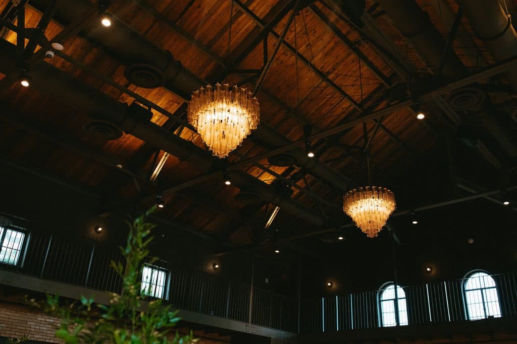 Industrial ceiling at indoor wedding venue with tiered chandeliers