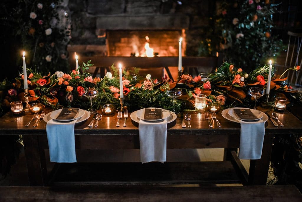 Farmhouse table for winter wedding in Maine with tapered candles and floral garland